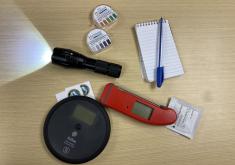 Restaurant inspection tools of the trade: a thermometer, a flashlight, test strips, and a notepad